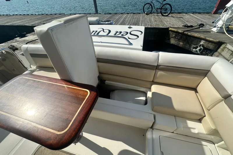 Slide: The Image of 2014 Sea Ray 450 Sedan Bridge yacht interior with cushioned seating and wooden table by the dock. - 23