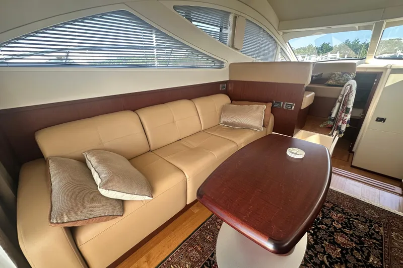 Slide: The Image of Luxurious interior of 2014 Sea Ray 450 Sedan Bridge with beige leather sofa and wooden table. - 28