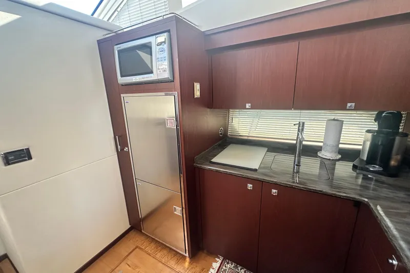 Slide: The Image of 2014 Sea Ray 450 Sedan Bridge yacht kitchen with microwave, fridge, and modern cabinetry. - 40