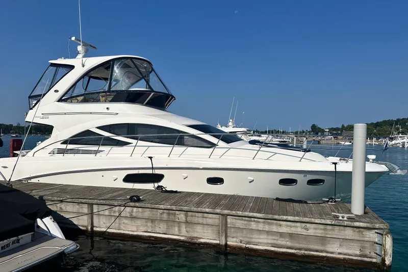 Slide: The Image of 2014 Sea Ray 450 Sedan Bridge yacht docked at marina under clear blue sky. - 5