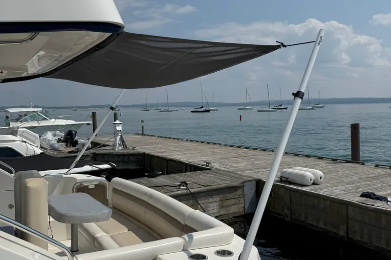 Slide: The Image of 2014 Sea Ray 450 Sedan Bridge yacht docked with sunshade, overlooking calm marina waters. - 80