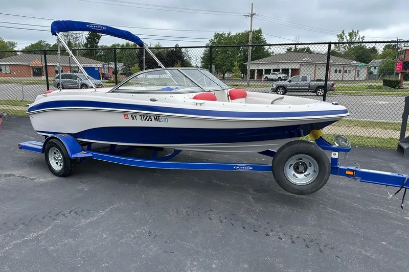 Slide: The Image of 2007 Tahoe Q4 Sport boat on trailer, parked outdoors with blue and white design. - 0