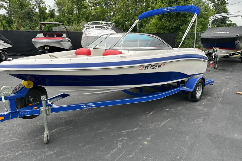 Slide: The Image of 2007 Tahoe Q4 Sport boat on trailer, blue and white, parked outdoors. - 2