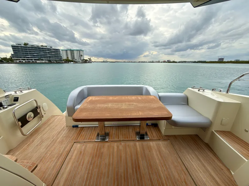 Slide: The Image of 2017 Beneteau Monte Carlo 5S yacht deck with seating, overlooking calm waters and modern buildings. - 20