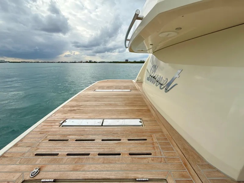 Slide: The Image of 2017 Beneteau Monte Carlo 5S yacht with wooden deck, overlooking calm waters and cloudy sky. - 21