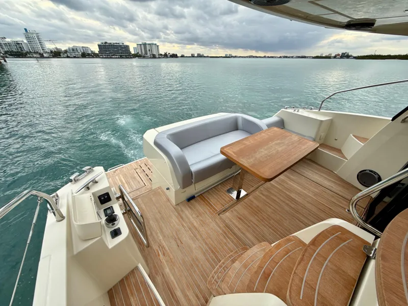 Slide: The Image of 2017 Beneteau Monte Carlo 5S yacht deck with seating and table, overlooking calm waters. - 26