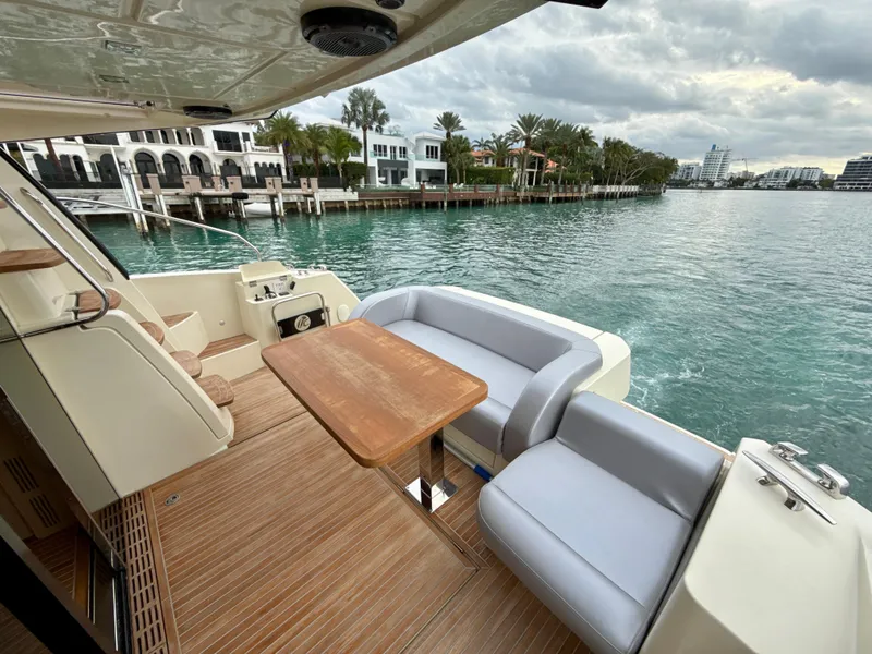 Slide: The Image of 2017 Beneteau Monte Carlo 5S yacht deck with seating and table, overlooking waterfront homes. - 27