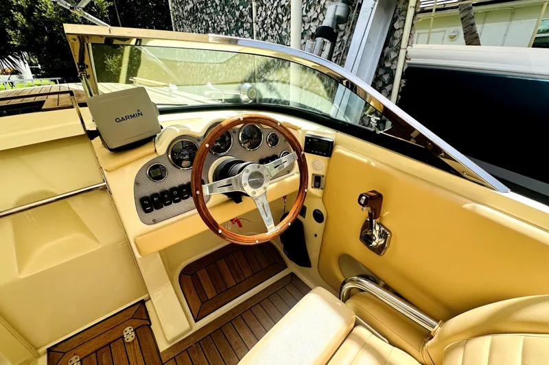 Slide: The Image of 2013 Chris-Craft Corsair 22 cockpit with Garmin navigation, wooden steering wheel, and beige interior. - 6