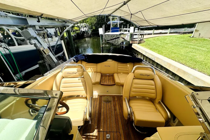 Slide: The Image of 2013 Chris-Craft Corsair 22 boat with tan leather seats and wooden deck under canopy. - 8