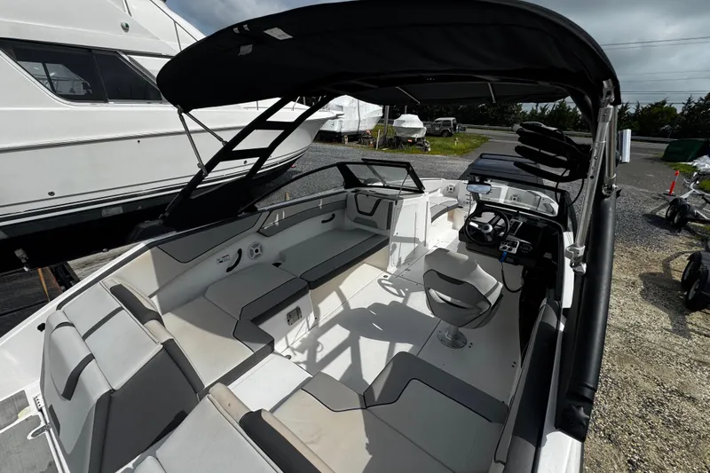 Slide: The Image of 2023 Yamaha Boats AR220 interior with seating and helm, docked outdoors. - 13