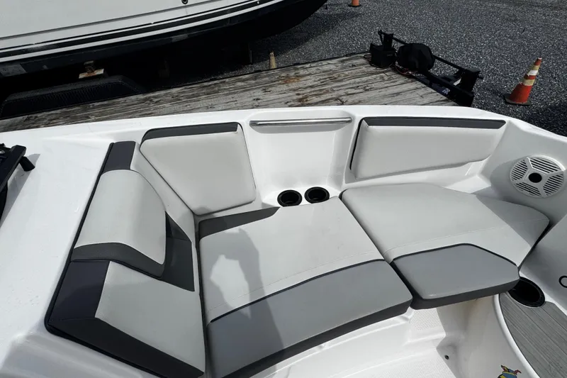 Slide: The Image of 2023 Yamaha Boats AR220 interior seating with gray upholstery and cup holders. - 7