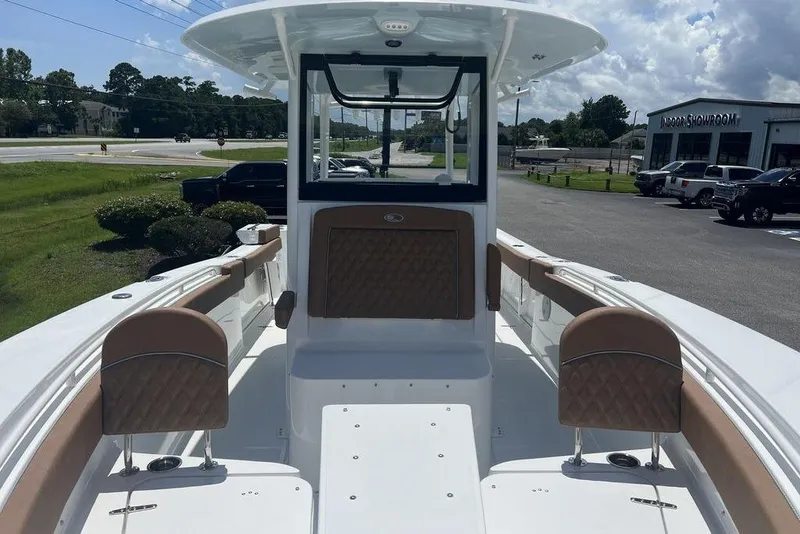 Slide: The Image of 2026 Sea Hunt Gamefish 30 Forward Seating boat with brown cushioned seats, parked outdoors. - 11