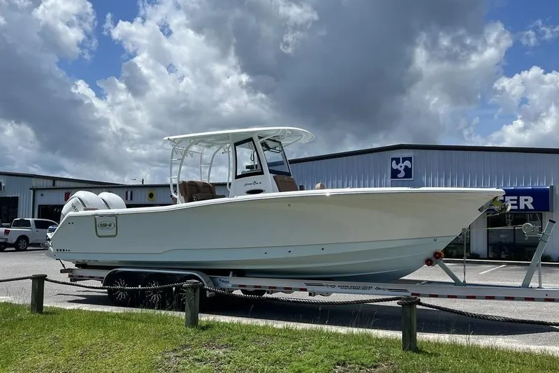 Slide: The Image of 2026 Sea Hunt Gamefish 30 boat on trailer, parked outside dealership under cloudy sky. - 7
