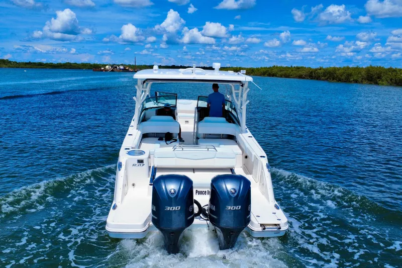 Slide: The Image of 2019 Robalo R317 Dual Console boat cruising on a sunny day with twin Yamaha engines. - 14