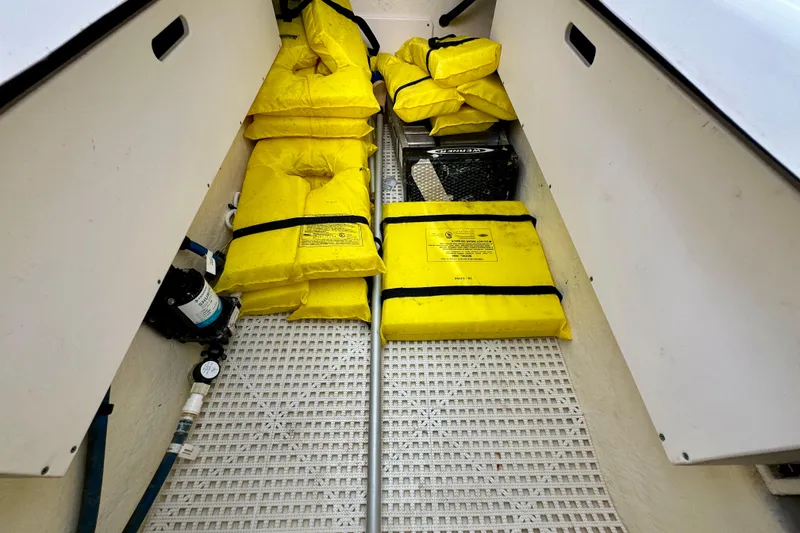 Slide: The Image of 2019 Robalo R317 Dual Console storage area with yellow life jackets and equipment. - 41