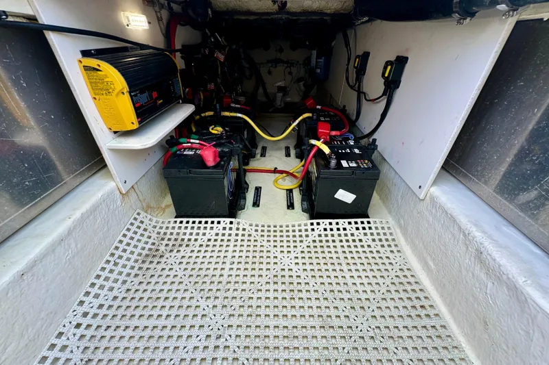 Slide: The Image of 2019 Robalo R317 Dual Console boat battery compartment with wiring and charger. - 44