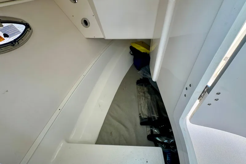 Slide: The Image of Interior cabin of 2019 Robalo R317 Dual Console boat, featuring storage space and porthole. - 55