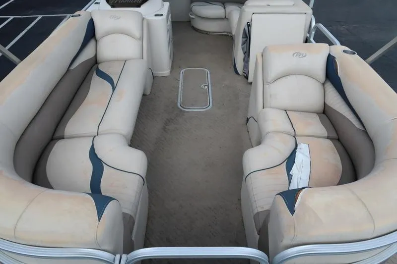 Slide: The Image of 2012 Manitou 24 Oasis Tri-Toon boat interior with beige seating and carpeted floor. - 10