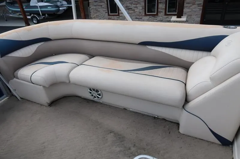 Slide: The Image of 2012 Manitou 24 Oasis Tri-Toon boat interior with beige and blue seating. - 11