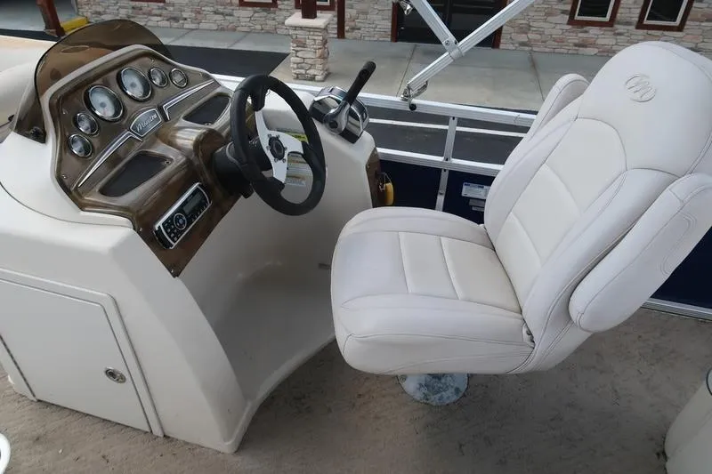 Slide: The Image of 2012 Manitou 24 Oasis Tri-Toon boat dashboard with steering wheel and captain's chair. - 14
