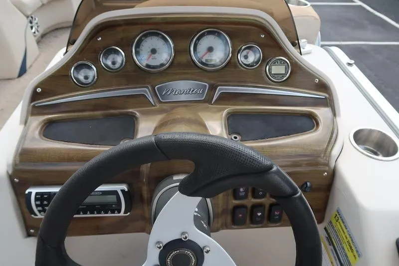Slide: The Image of Steering console of 2012 Manitou 24 Oasis Tri-Toon with wood finish and gauges. - 19