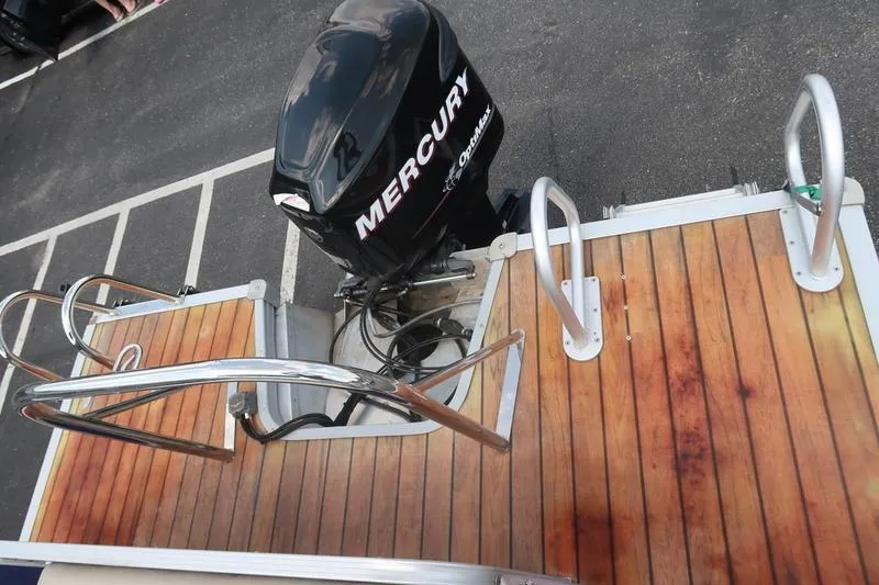 Slide: The Image of 2012 Manitou 24 Oasis Tri-Toon with Mercury outboard motor and wooden deck. - 20