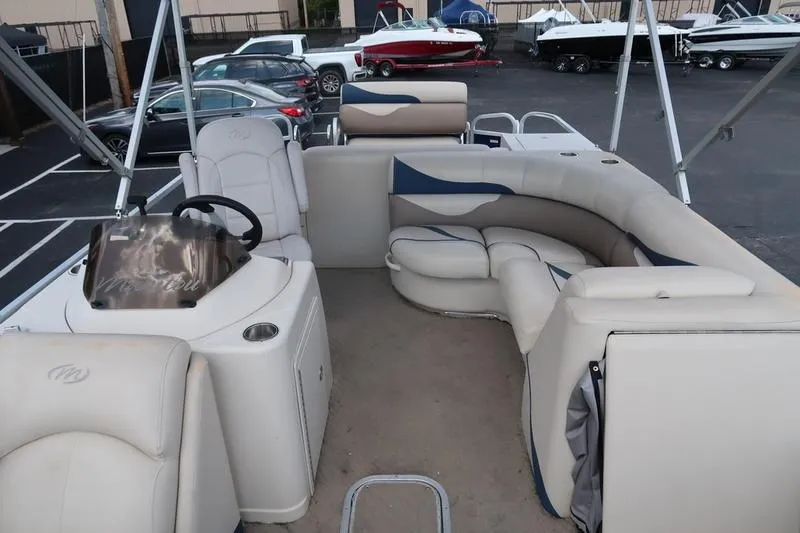 Slide: The Image of 2012 Manitou 24 Oasis Tri-Toon boat interior with plush seating and steering console. - 4