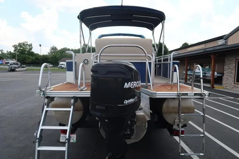 Slide: The Image of 2012 Manitou 24 Oasis Tri-Toon boat with Mercury outboard motor, parked in a lot. - 5