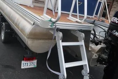 Slide: The Image of 2012 Manitou 24 Oasis Tri-Toon boat with rear ladder and outboard motor. - 7