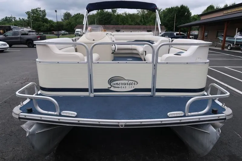 Slide: The Image of 2002 Lowe Trinidad 200 pontoon boat, rear view, parked in a lot with trees and buildings. - 6