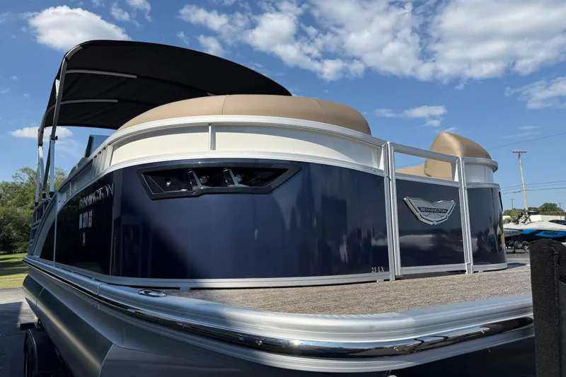 Slide: The Image of 2025 Bennington 23 LXSFB pontoon boat with canopy, blue and white design, under a clear sky. - 3