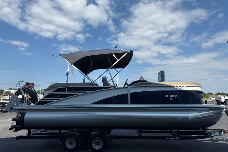Slide: The Image of 2025 Bennington 23 LXSFB pontoon boat on trailer under blue sky. - 5