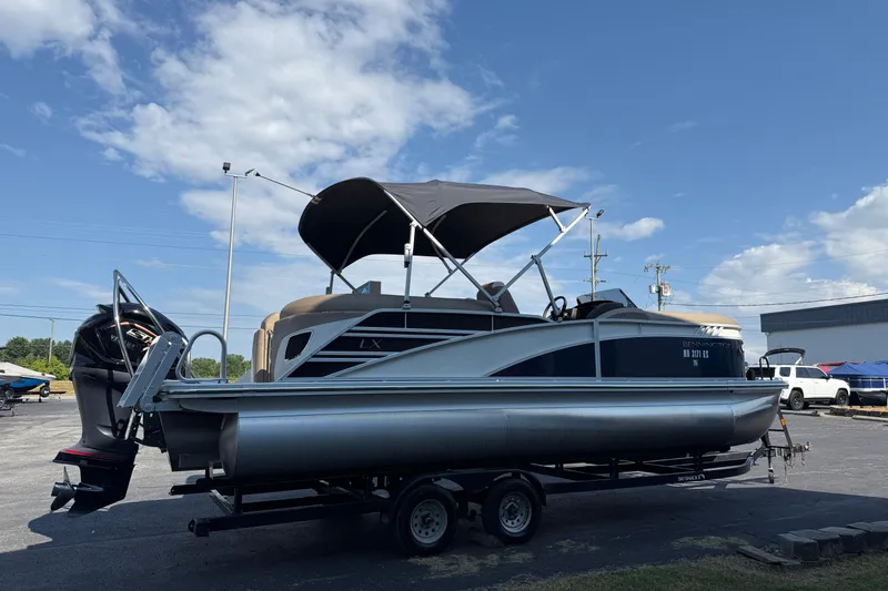 Slide: The Image of 2025 Bennington 23 LXSFB pontoon boat on trailer under blue sky. - 6