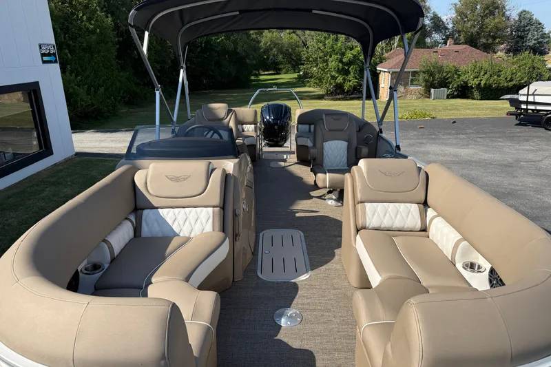 Slide: The Image of 2025 Bennington 23 LXSFB pontoon boat with luxurious seating and canopy, parked outdoors. - 9