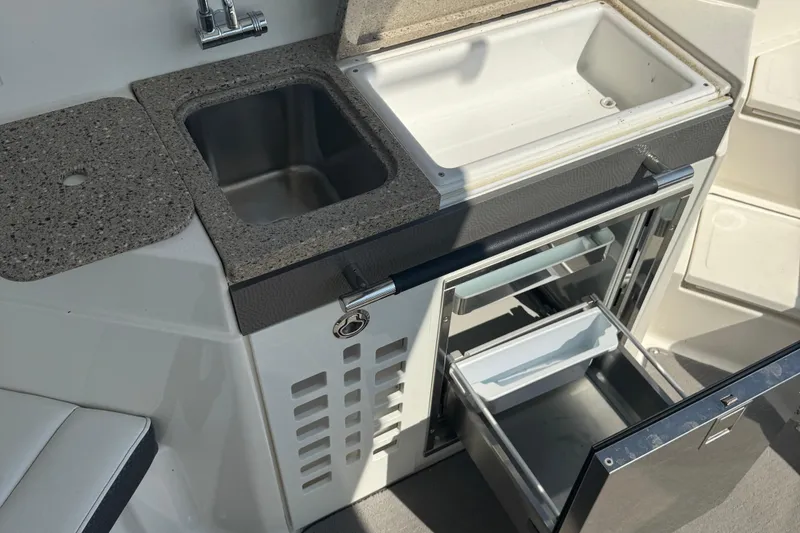 Slide: The Image of 2016 Sea Ray 350 SLX boat kitchenette with sink and open storage compartments. - 14