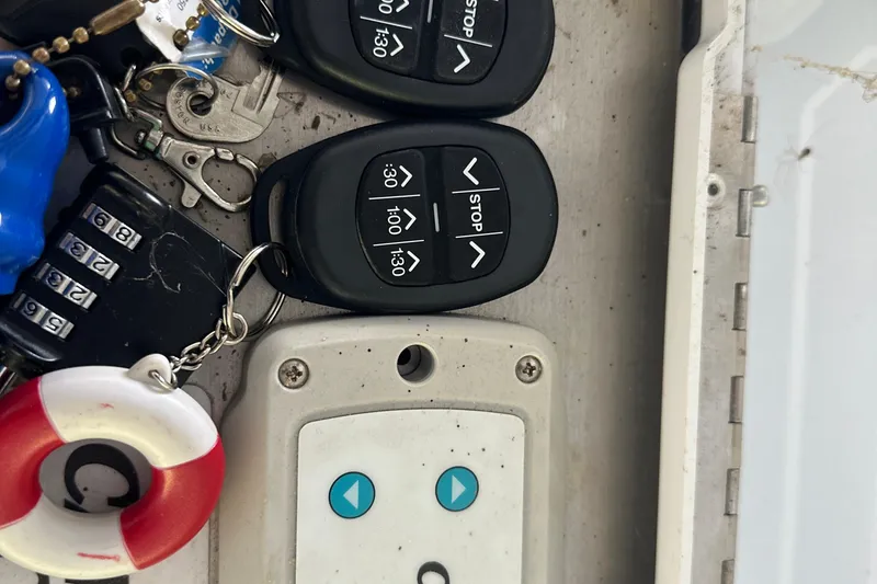 Slide: The Image of Remote controls and keys on a 2005 Crownline 270 BR boat dashboard. - 46