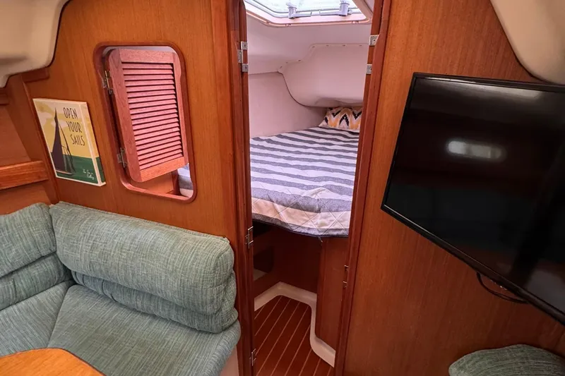 Slide: The Image of Interior of a 1997 Hunter 340 sailboat with cozy cabin and striped bedding. - 7