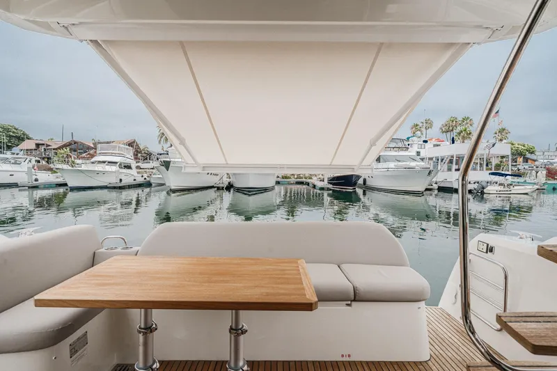Slide: The Image of Prestige 420 Fly 2021 yacht interior with marina view, featuring a wooden table and cushioned seating. - 31