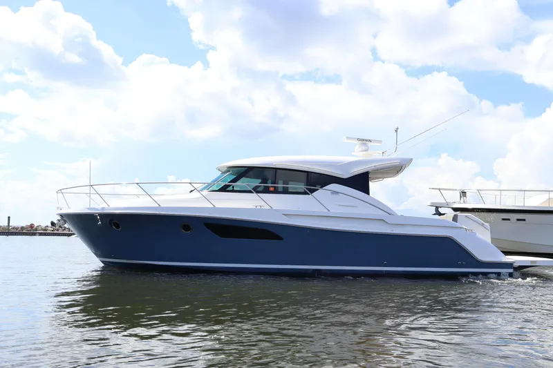 Slide: The Image of 2020 Tiara Yachts C44 Coupe cruising on calm waters under a cloudy sky. - 12