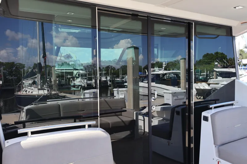 Slide: The Image of 2020 Tiara Yachts C44 Coupe with reflective glass doors at a marina. - 15