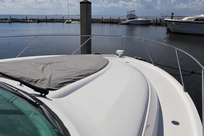 Slide: The Image of 2020 Tiara Yachts C44 Coupe bow view at marina, featuring sleek design and water backdrop. - 25