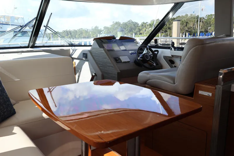 Slide: The Image of Interior of 2020 Tiara Yachts C44 Coupe, featuring helm and polished wooden table. - 36