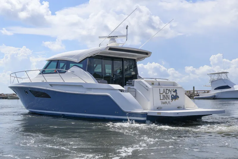Slide: The Image of 2020 Tiara Yachts C44 Coupe cruising on water under a partly cloudy sky. - 4
