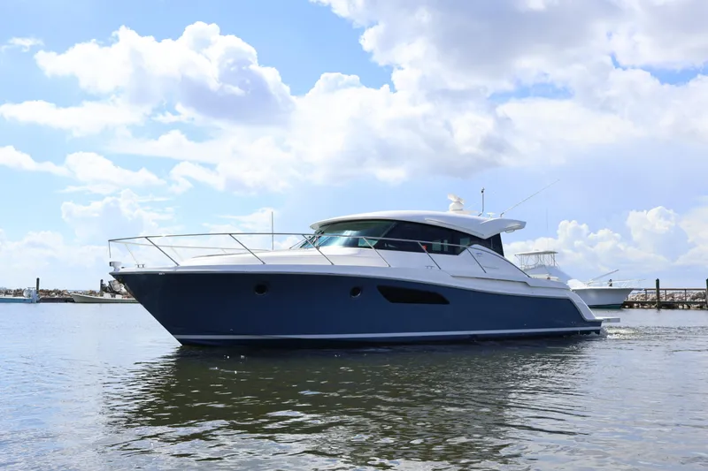 Slide: The Image of 2020 Tiara Yachts C44 Coupe cruising on calm waters under a partly cloudy sky. - 9