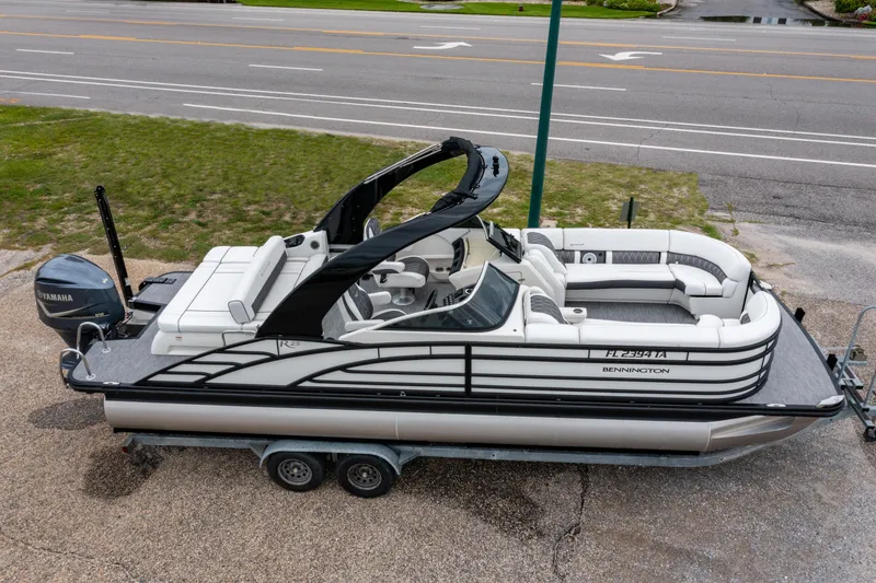 Slide: The Image of 2021 Bennington R25 Sport pontoon boat on trailer, featuring sleek design and spacious seating. - 0