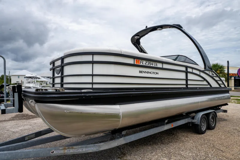 Slide: The Image of 2021 Bennington R25 Sport pontoon boat on trailer, parked outdoors under cloudy sky. - 10