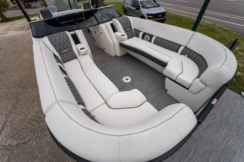 Slide: The Image of 2021 Bennington R25 Sport boat with luxurious white and gray seating, parked on pavement. - 12
