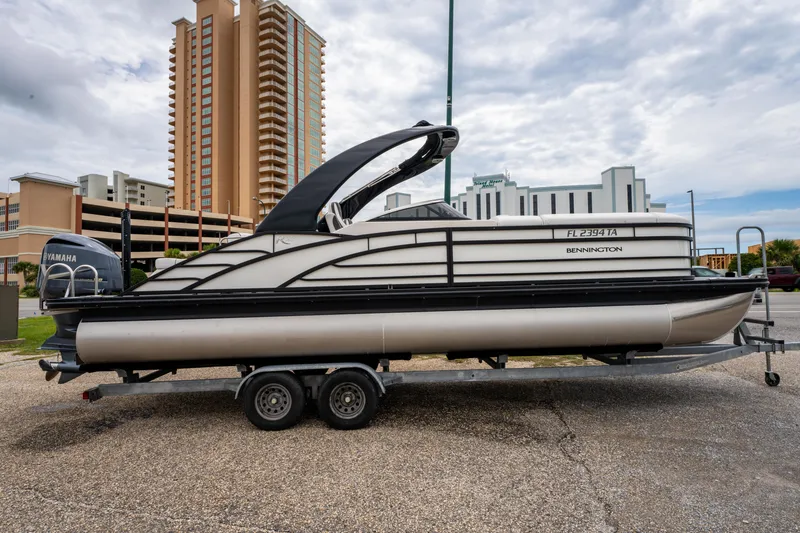 Slide: The Image of 2021 Bennington R25 Sport pontoon boat on trailer, urban background, overcast sky. - 4