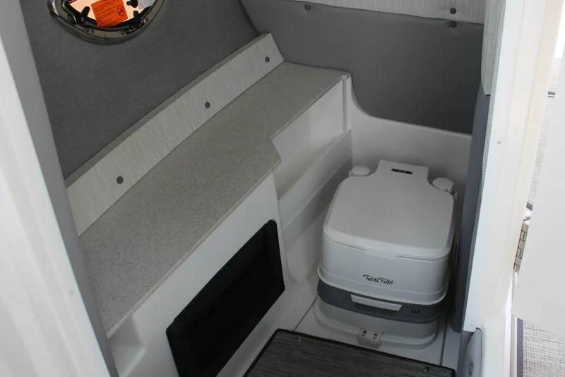 Slide: The Image of 2025 Cobalt R8 Surf boat interior with compact toilet and storage area. - 11
