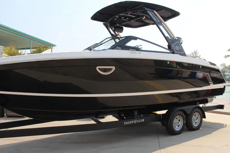 Slide: The Image of 2025 Cobalt R8 Surf boat on trailer, sleek black design, docked outdoors. - 9